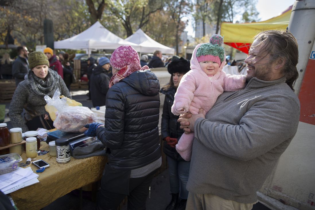 Paul Dench-Layton, of Violet Hill Farm, holds his daughter Lillianna Grace, as customers pick up their Thanksgiving turkeys at the Union Square Farmers Market, in New York<br/>